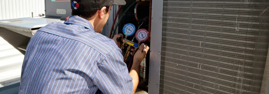 HVAC technician servicing a condenser unit in Royal Kunia